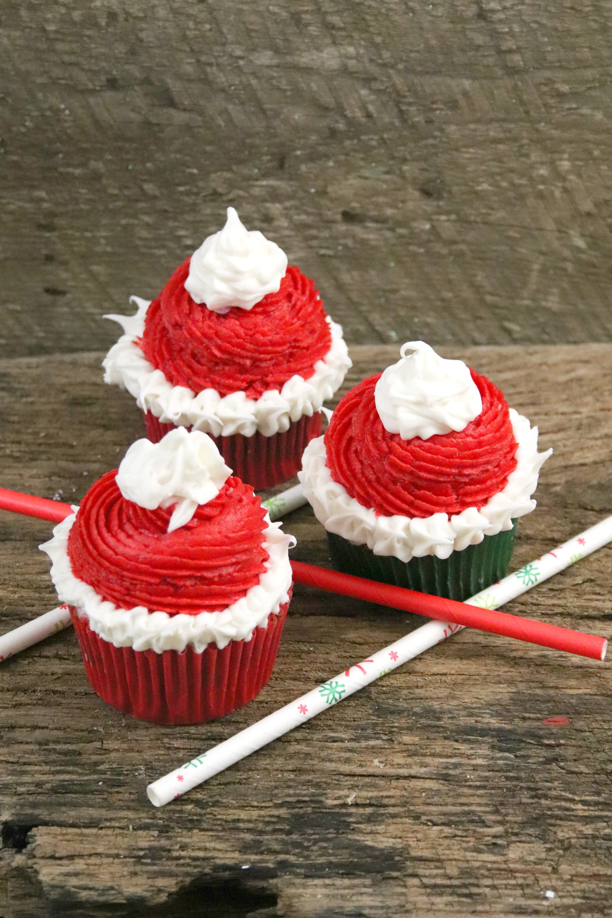 These fun a festive Santa hat Christmas Cupcakes are super fun to make with kids! The recipe features a cocoa buttercream frosting perfect for the season! The red and green inside makes a fun treat for kids! #holidaybaking #christmascupcakes #