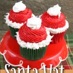 These fun a festive Santa hat Christmas Cupcakes are super fun to make with kids! The recipe features a cocoa buttercream frosting perfect for the season! The red and green inside makes a fun treat for kids! #holidaybaking #christmascupcakes