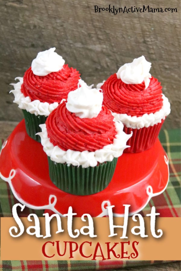 These fun a festive Santa hat Christmas Cupcakes are super fun to make with kids! The recipe features a cocoa buttercream frosting perfect for the season! The red and green inside makes a fun treat for kids! #holidaybaking #christmascupcakes 