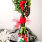 This Christmas Table DIY centerpiece is super easy to make and great to give as a hostess gift! This craft uses simple materials you likely have at home! This craft uses a wine bottle, modge podge, tulle and ribbon for a beautiful centerpiece that will level up your Christmas decor! #ChristmasDIY #ChristmasDecor #diychristmas #christmascenterpiece