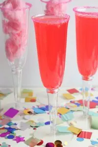 This fun and sweet non alcoholic tasty cotton candy mocktail has a very beautiful and festive pink color! This is a super fun drink to make for kids or non drinkers at a party! The recipe calls for cotton candy, pink sugar and strawberry soda which makes for a pretty sparking pink drink. This is a great sparkling drink recipe for a crowd! Your guests will be so impressed! #mocktail #nonalcoholicdrinks #nonalcoholic #mocktailrecipe