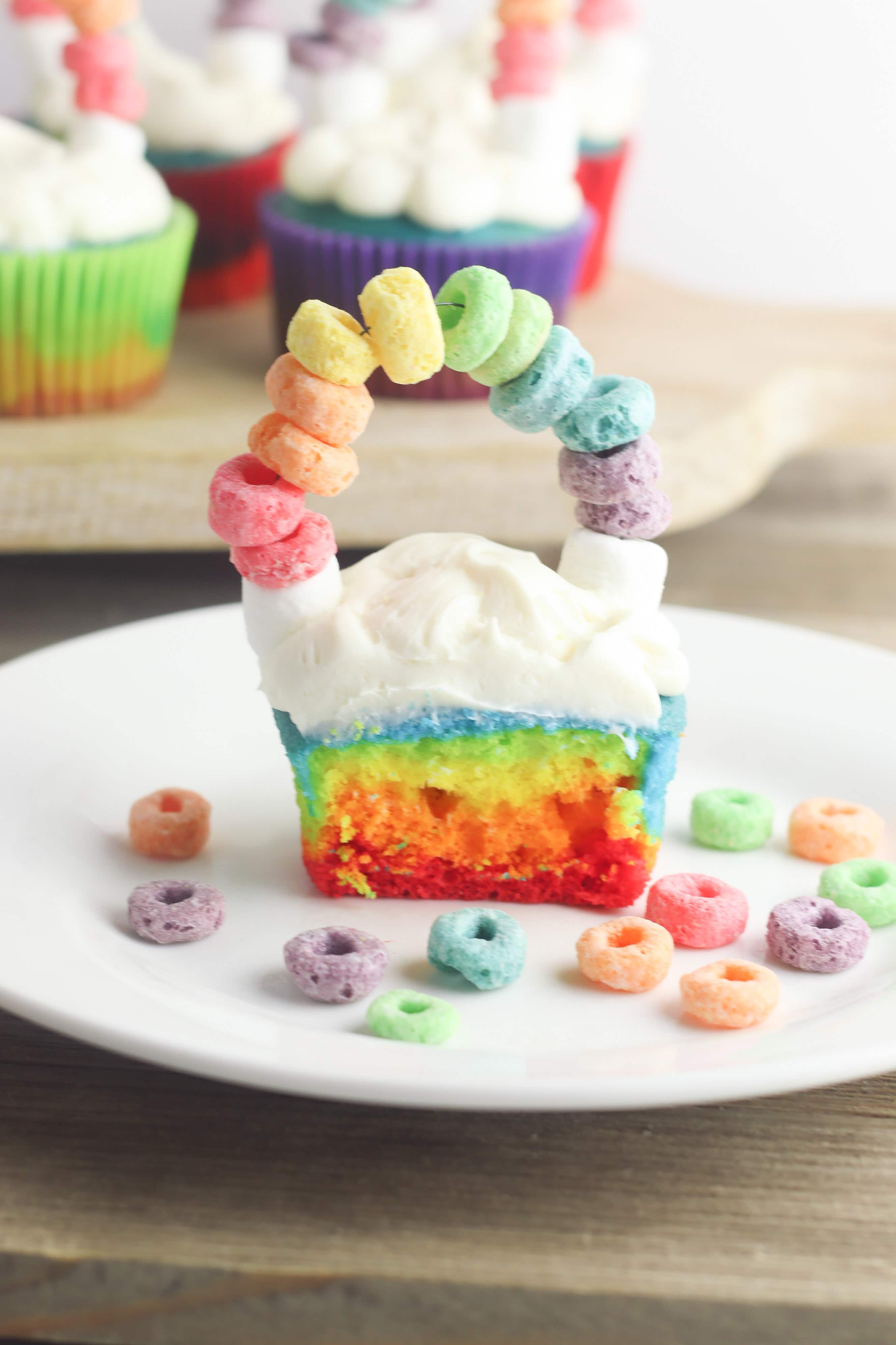 St. Patrick's Day is coming and I have got the most perfect Rainbow St. Patrick's Day Cupcakes for you to make with the kids! These cupcakes not only look beautiful but they are tasty too! Made with different colors on each layer and fruit loops for a fun rainbow on top of clouds. These are perfect for classrooms and other festive party events! #cupcakes #stpaddysday #stpatricksday #luckoftheirish #rainbowcupcakes