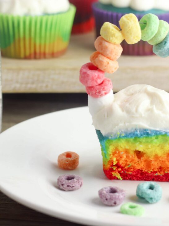 St. Patrick's Day is coming and I have got the most perfect Rainbow St. Patrick's Day Cupcakes for you to make with the kids! These cupcakes not only look beautiful but they are tasty too! Made with different colors on each layer and fruit loops for a fun rainbow on top of clouds. These are perfect for classrooms and other festive party events! #cupcakes #stpaddysday #stpatricksday #luckoftheirish #rainbowcupcakes