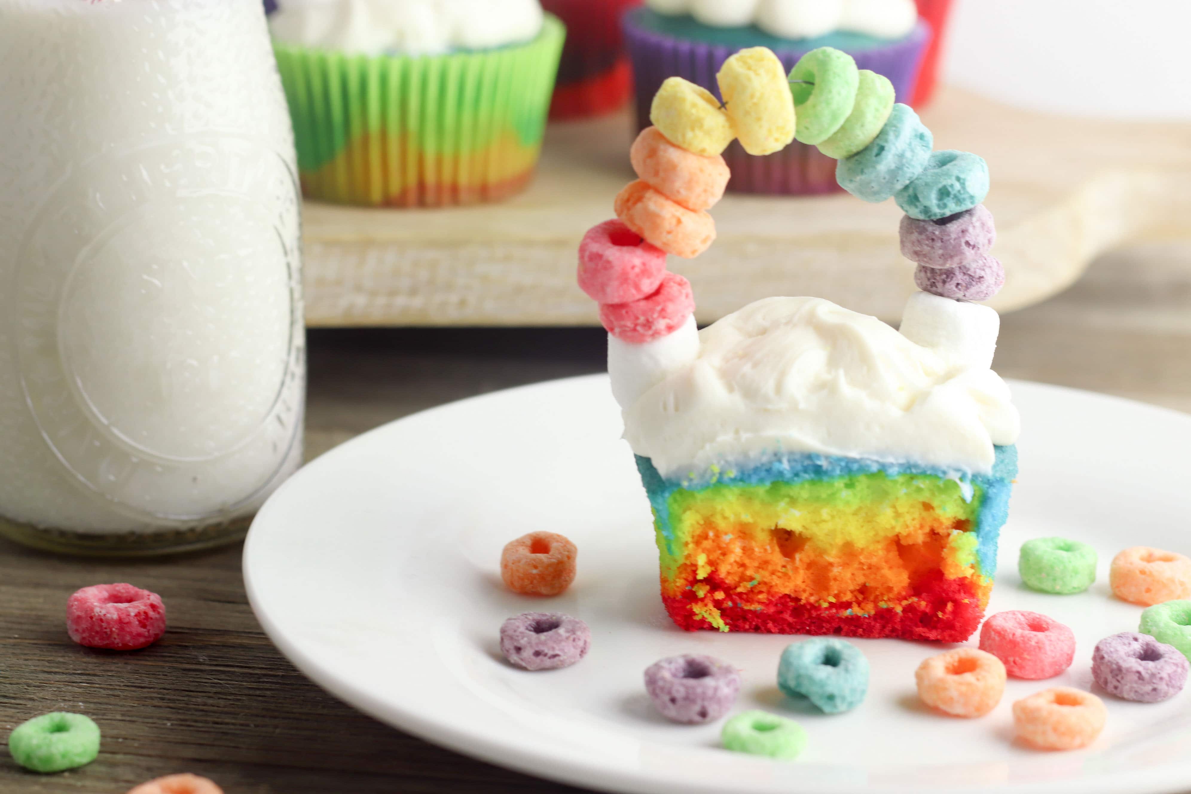 St. Patrick's Day is coming and I have got the most perfect Rainbow St. Patrick's Day Cupcakes for you to make with the kids! These cupcakes not only look beautiful but they are tasty too! Made with different colors on each layer and fruit loops for a fun rainbow on top of clouds. These are perfect for classrooms and other festive party events! #cupcakes #stpaddysday #stpatricksday #luckoftheirish #rainbowcupcakes