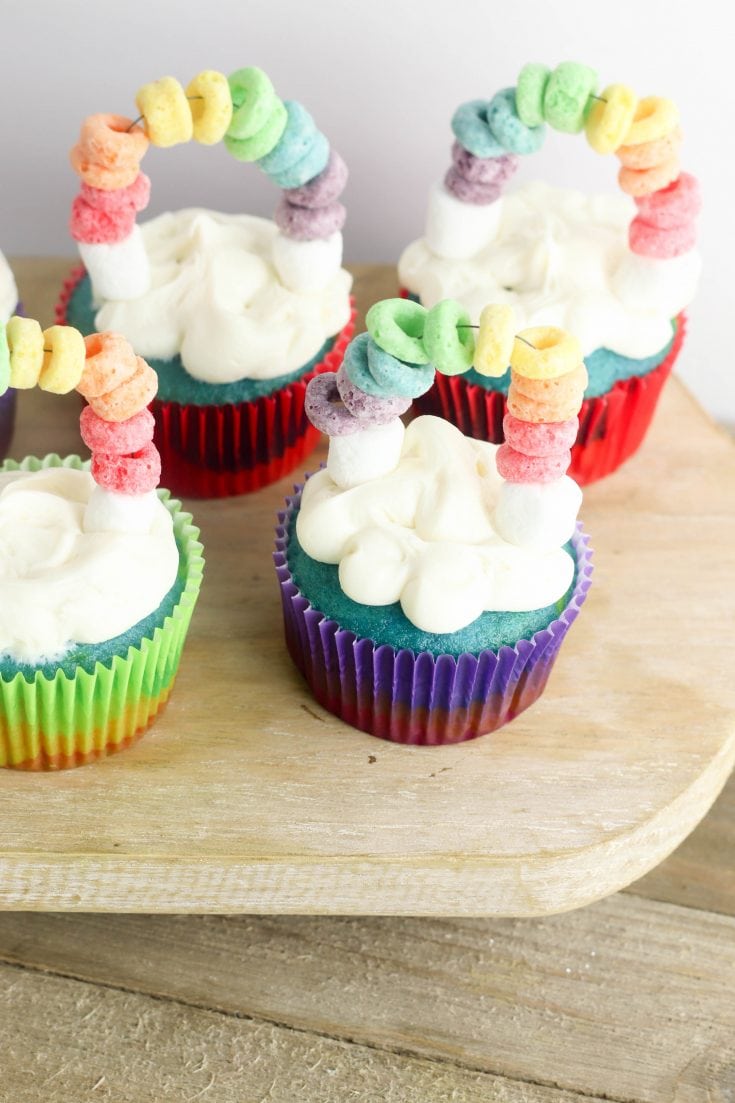 St. Patrick's Day is coming and I have got the most perfect Rainbow St. Patrick's Day Cupcakes for you to make with the kids! These cupcakes not only look beautiful but they are tasty too! Made with different colors on each layer and fruit loops for a fun rainbow on top of clouds. These are perfect for classrooms and other festive party events! #cupcakes #stpaddysday #stpatricksday #luckoftheirish #rainbowcupcakes