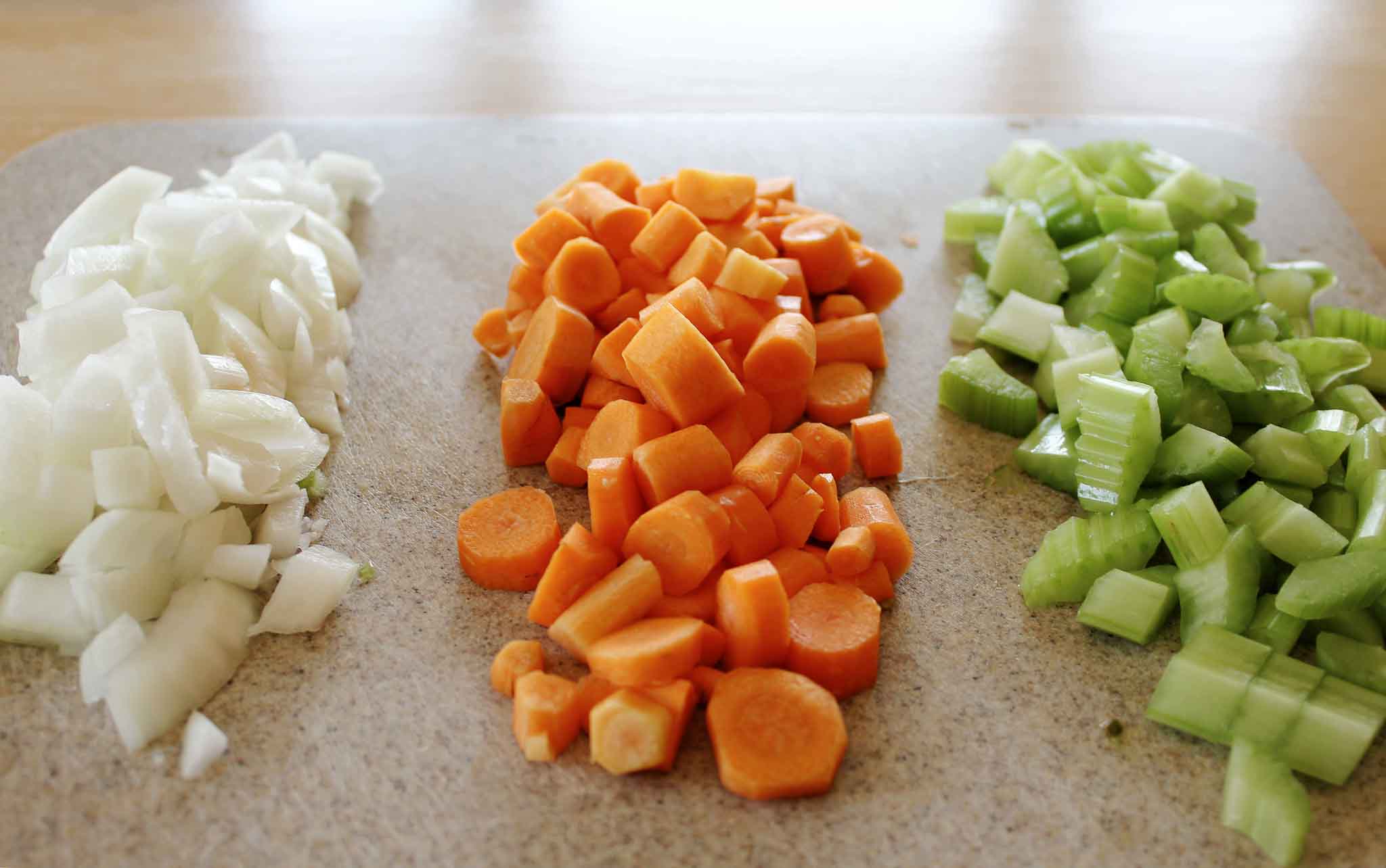 chopped onions, carrots and celery on a cutting board