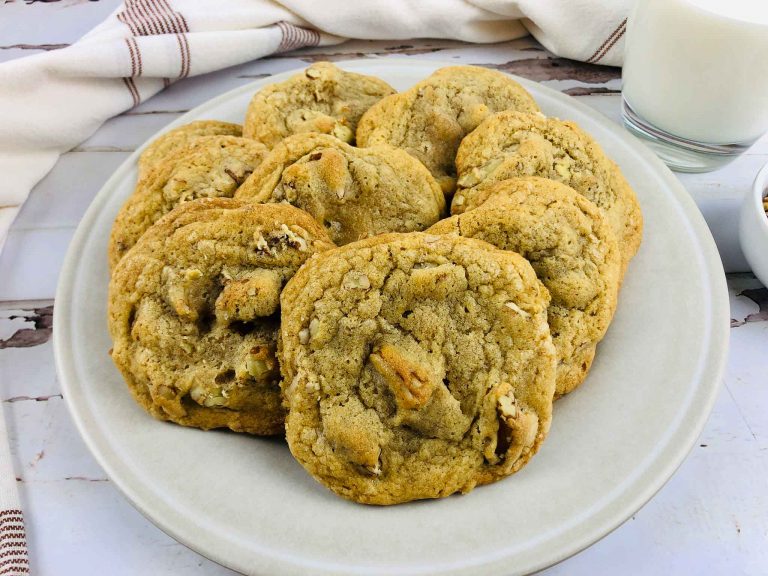 a dozen butter pecan cookies on a white plate with a white kitchen cloth behind it