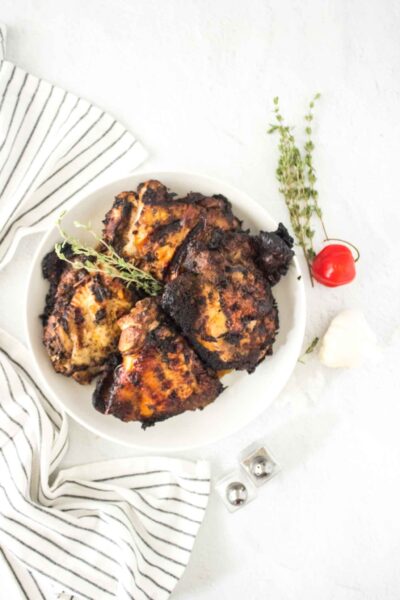 four pieces of jerk chicken with decorative thyme and scotch bonnet pepper