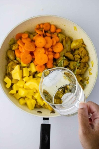 Authentic Jamaican Curry Chicken pouring water in pot