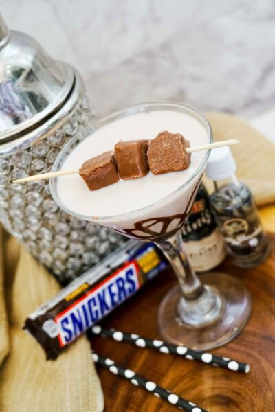 snickers martini in a martini glass in front of a cocktail shaker