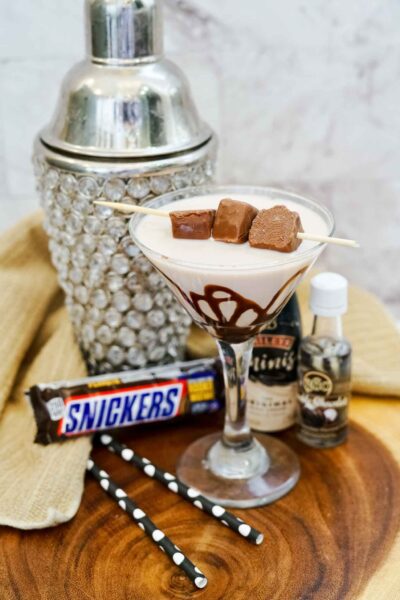 snickers martini in a martini glass in front of a cocktail shaker